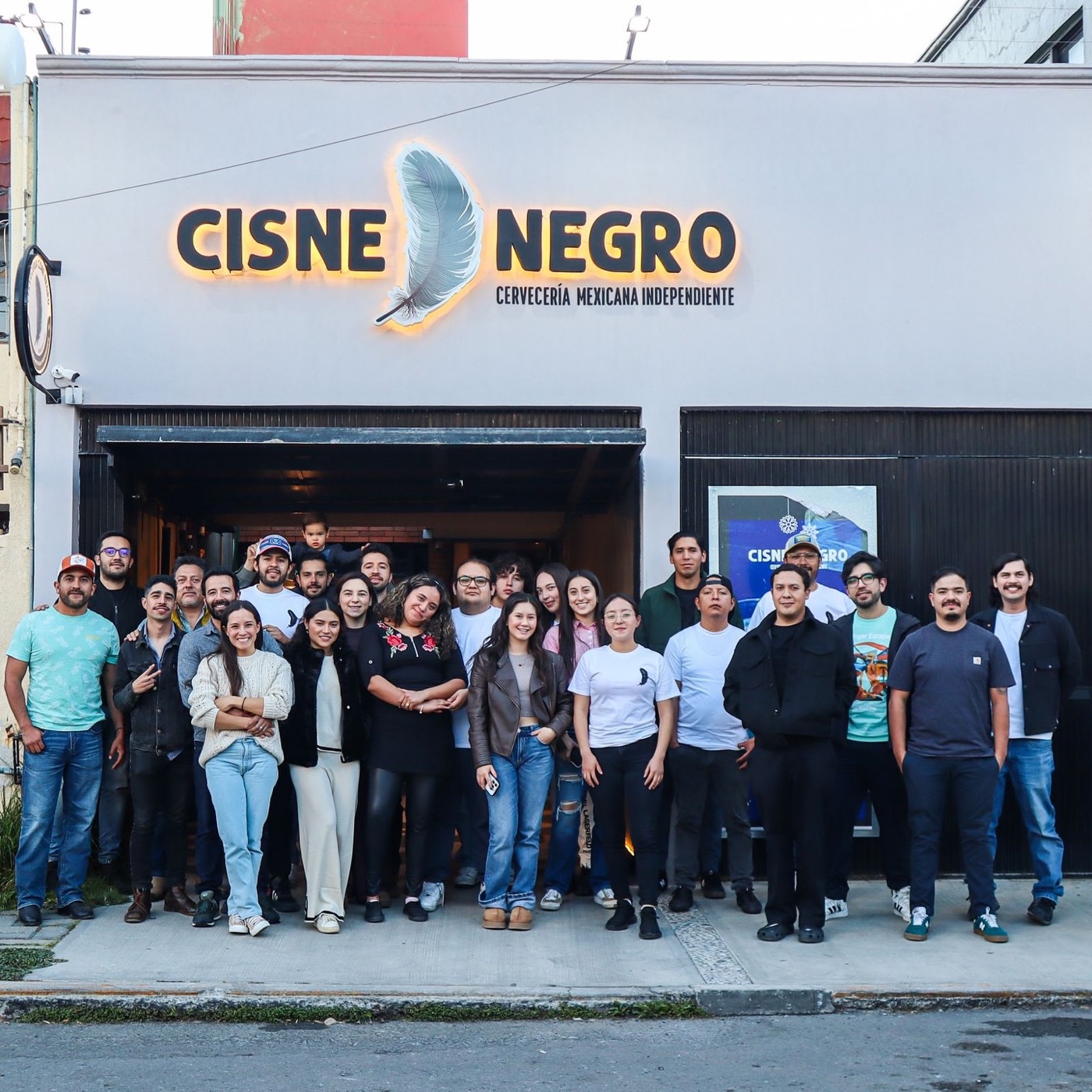 Equipo y amigos de Cisne Negro posan frente a la fachada de la cervecería en su primer aniversario