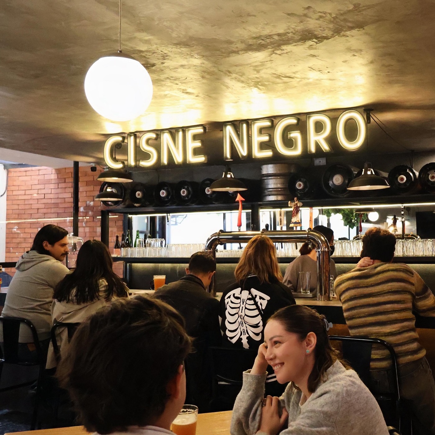 Taproom lleno bajo el letrero de neón de Cisne Negro