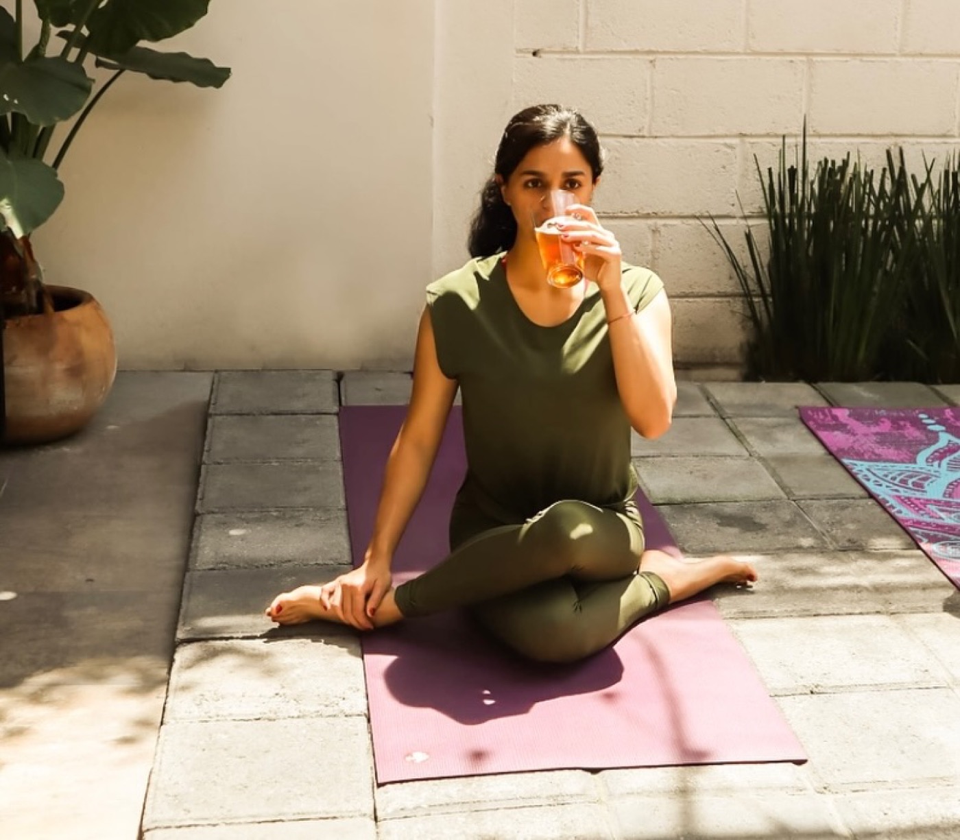 Una asistente prueba su cerveza sentada en su tapete durante la sesión de yoga y cerveza